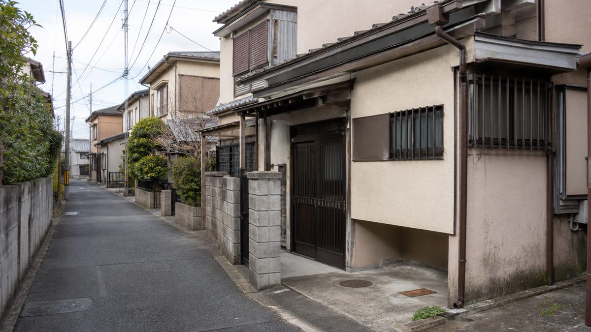 幅の狭い住宅街の道路と古い一戸建て