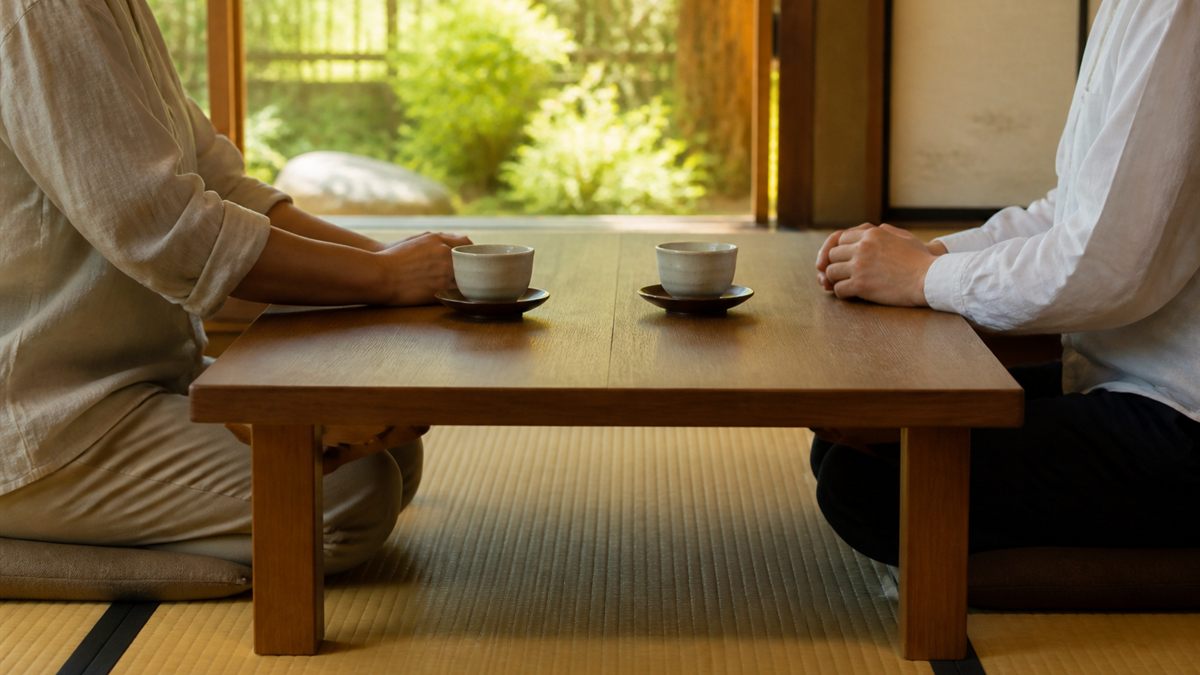 湯呑みを挟んで向かい合う親子の手元
