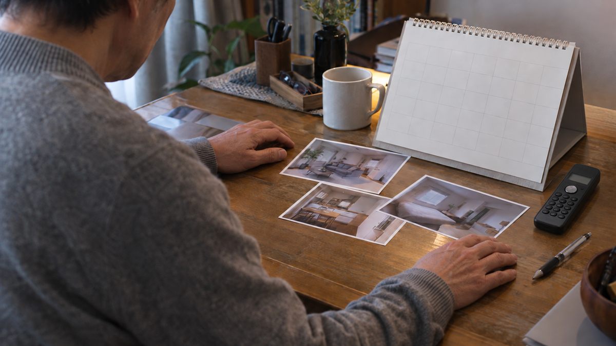 自宅の机で実家の写真と予定表を見ながら準備している場面