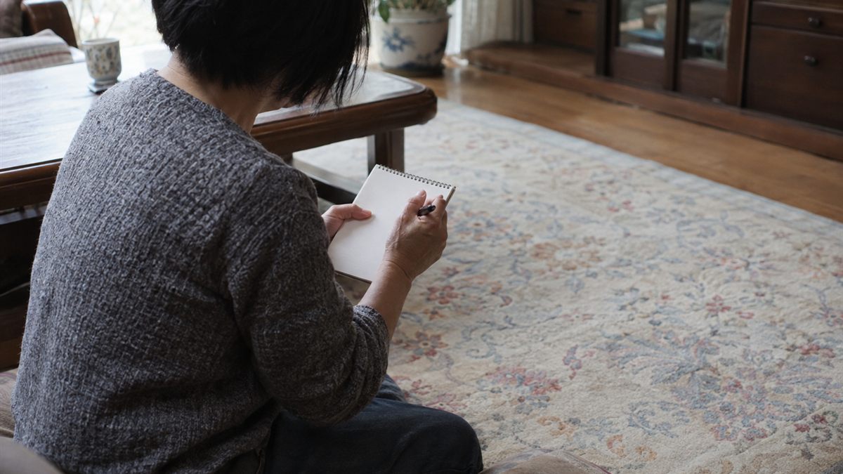 居間の大きなカーペットと手元のメモを見比べている場面