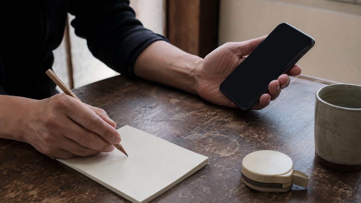 台所でスマートフォンを見ながらメモを取る手元