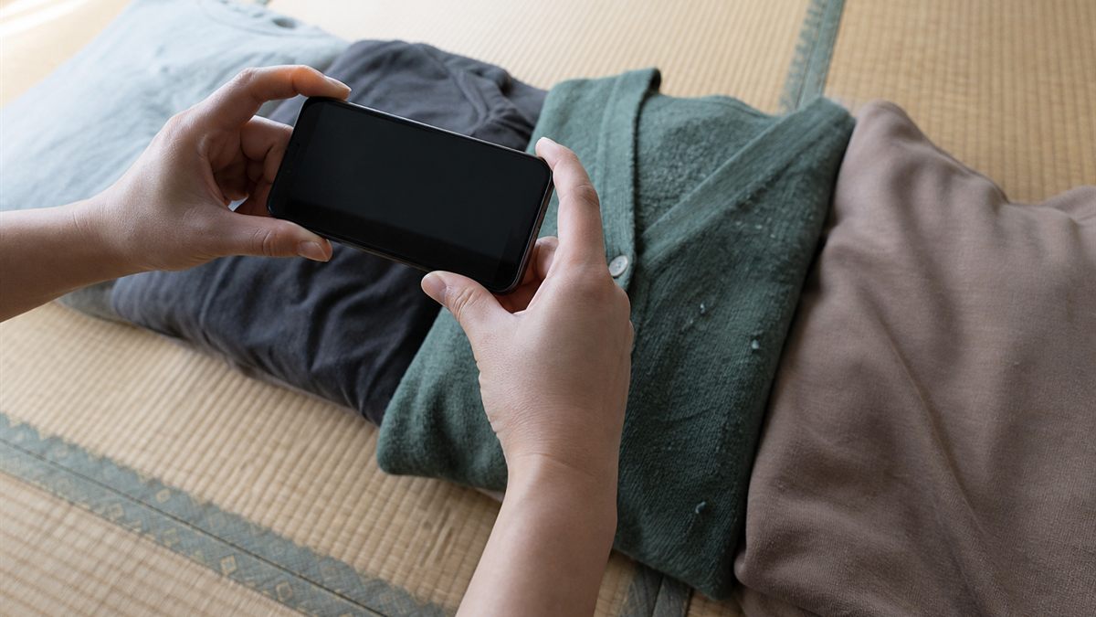 分ける前の衣類をスマートフォンで撮っている手元