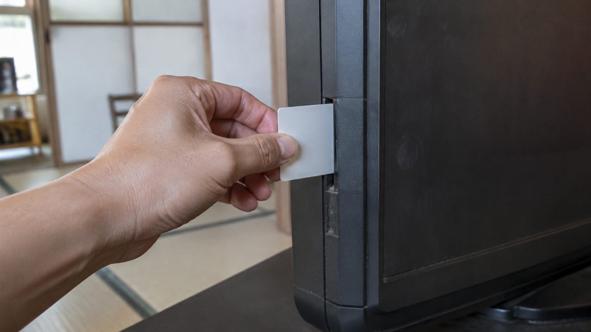テレビ側面のスロットからカードを抜き取る手元