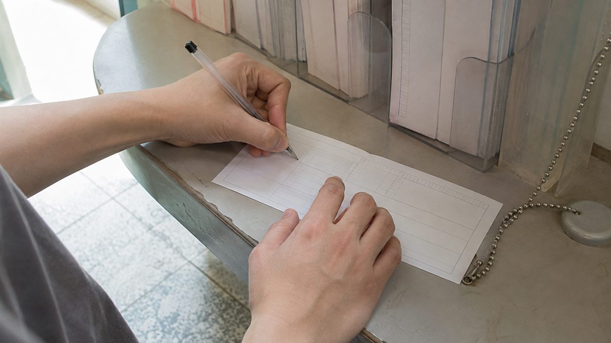 郵便局の記入台で払込用紙に書き込む手元